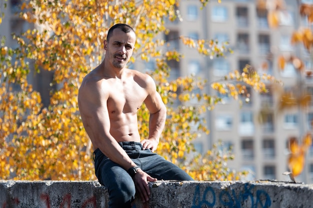 Portrait of Muscular Man Sitting on Old Rooftop