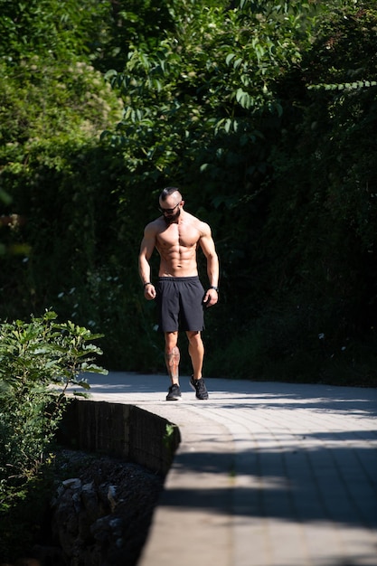 強い屋外に立っている筋肉の男の肖像画