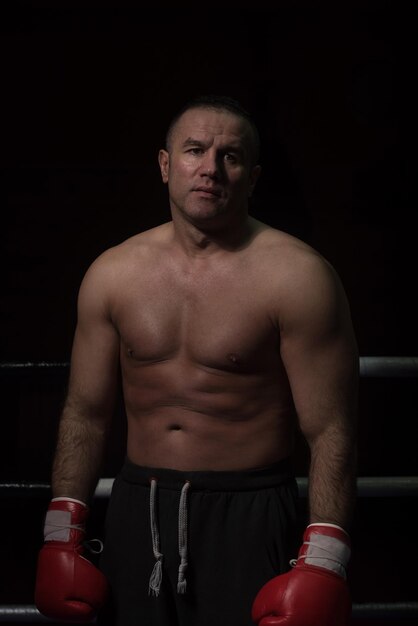 portrait of muscular professional kickboxer who standing in the ring while training for the fight