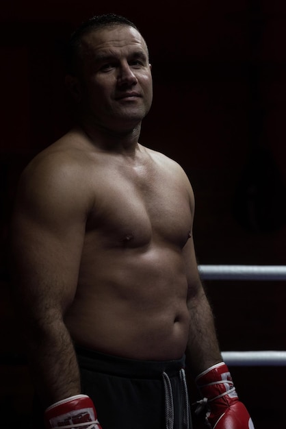 portrait of muscular professional kickboxer who standing in the ring while training for the fight