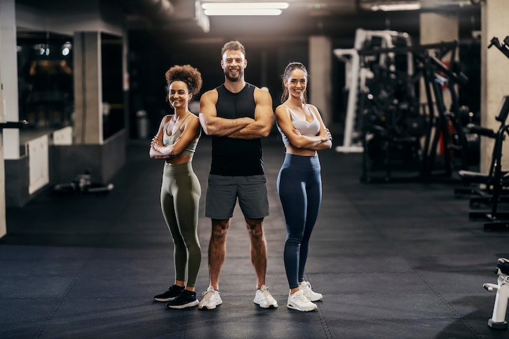 Photo portrait of muscular sportspeople in shape posing in a gym while smiling at the camera