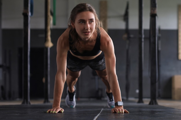 Portrait of a muscular woman on a plank position.