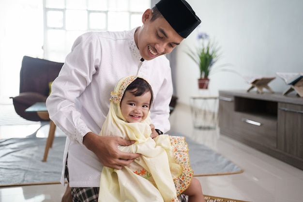 Portrait of muslim father teaching her cute daughter how to pray at home