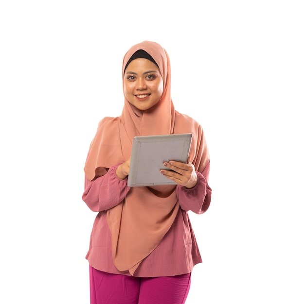 Portrait of muslimah in hijab standing using tablet on isolated background with copyspace