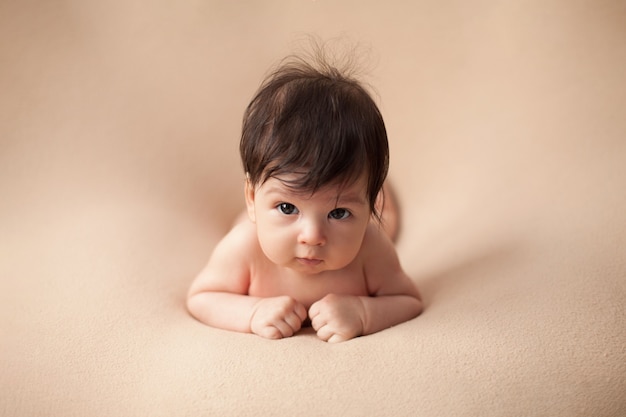 Ritratto di un bambino nudo con capelli scuri e grandi occhi sdraiati