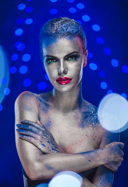 Portrait of naked woman with glitter against blue background