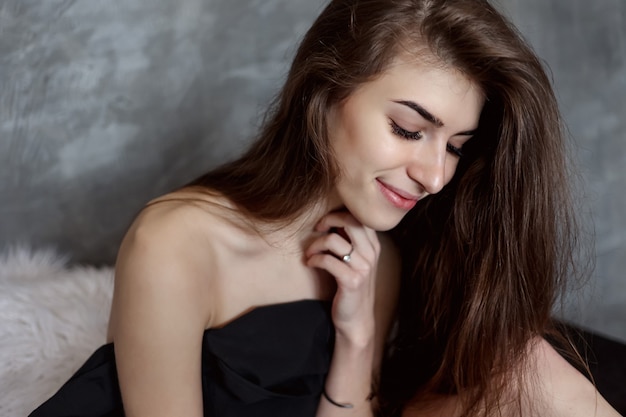 Portrait of natural nice woman covering herself with black sheet in dark room