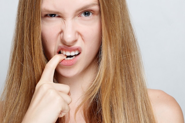 Portrait of nervous pretty young woman biting her nails