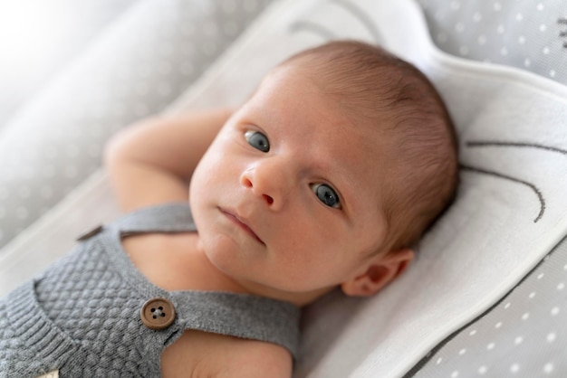 Portrait of a newborn baby in bed looking at the camera