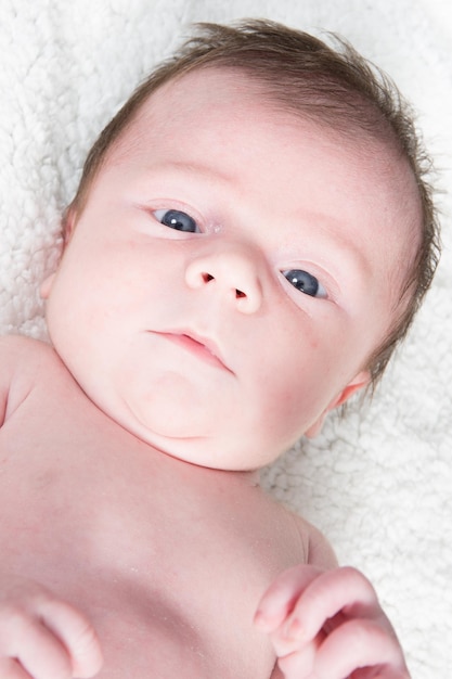 Portrait of a newborn baby lying on a white towel