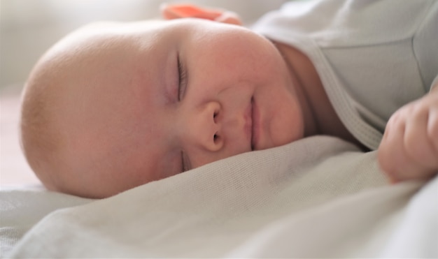 Portrait of a newborn baby sleeping on a white blanket.