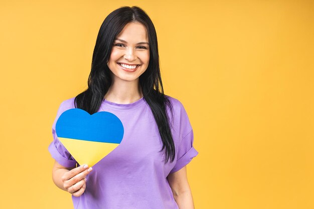 Portrait of nice beautiful lovely glad cheerful woman holding in hands Ukrainian flag having fun isolated over yellow pastel color background