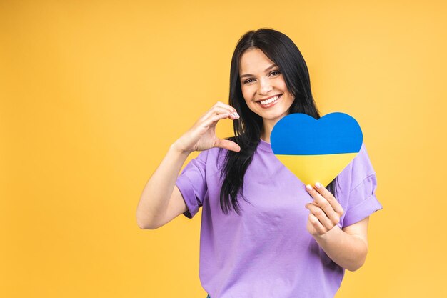 Portrait of nice beautiful lovely glad cheerful woman holding in hands ukrainian flag having fun isolated over yellow pastel color background