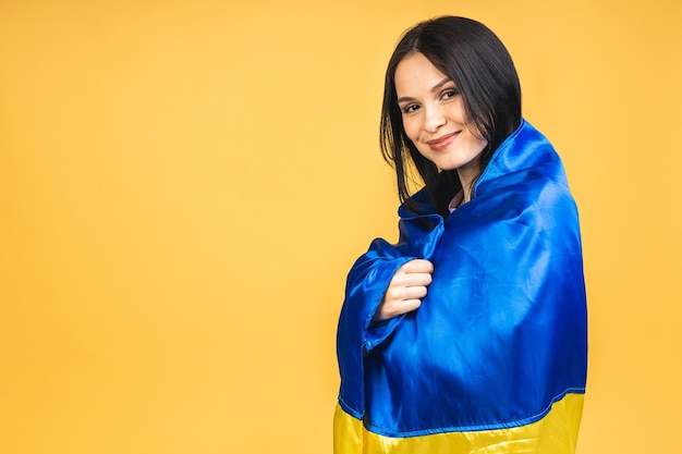 Portrait of nice beautiful lovely glad cheerful woman holding in hands Ukrainian flag having fun isolated over yellow pastel color background