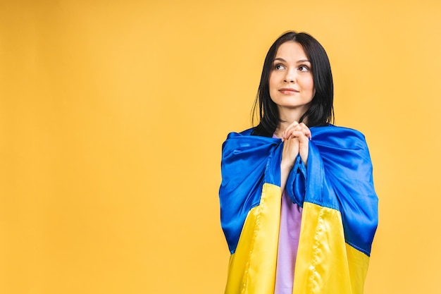 Portrait of nice beautiful lovely glad cheerful woman holding in hands Ukrainian flag having fun isolated over yellow pastel color background