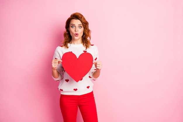 Portrait   nice-looking attractive lovely lovable cheerful amazed  girl wearing white pullover holding in hands large heart