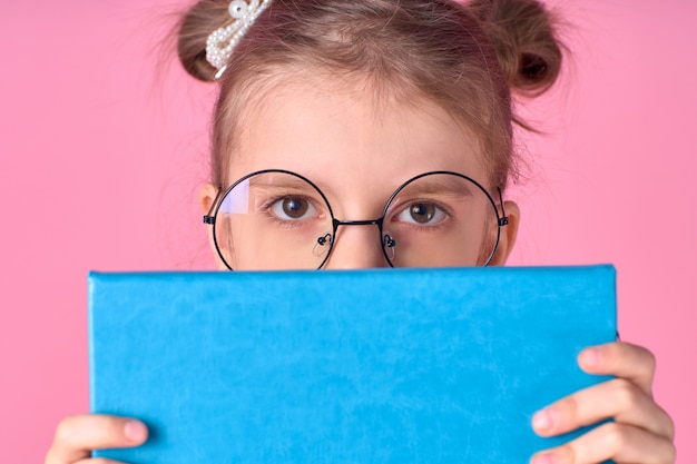 Portrait of nice lovely attractive cheerful school girl hiding behind opened book