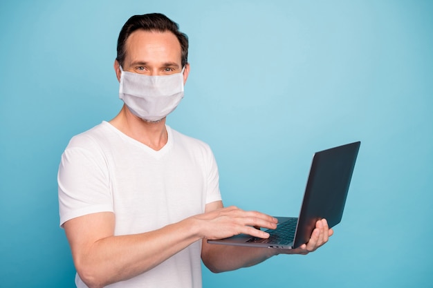 Portrait of nice skilled guy wearing safety mask working remotely on laptop watch video lesson