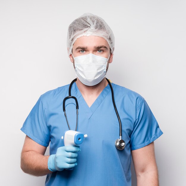 Portrait of nurse holding infrared thermometer