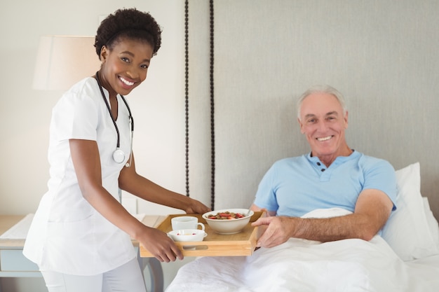 Portrait of nurse serving breakfast to senior patient