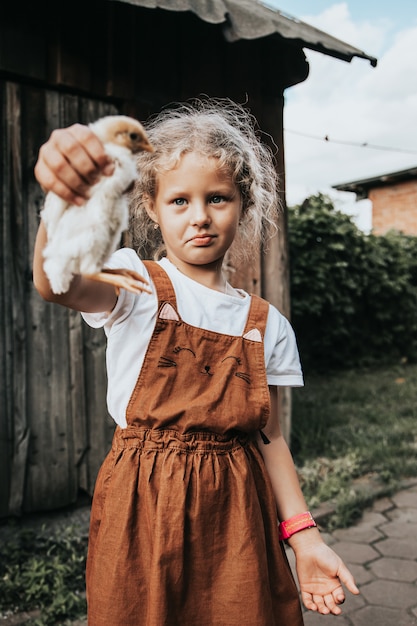 Портрет красивой девушки, которая держит в руках маленькую желтую курицу