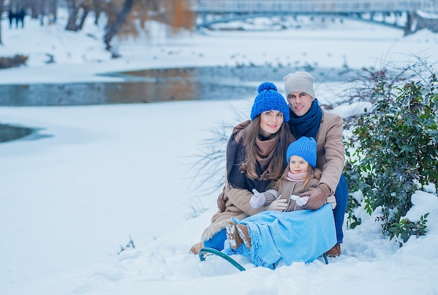 공원에서 얼어 붙은 호수의 배경에 베이지 색과 파란색 옷을 입고 아름다운 젊은 가족의 초상화