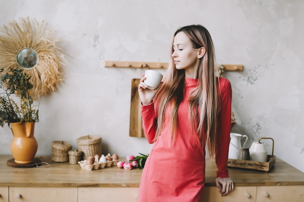 Портрет красивой молодой женщины, пьющей чай или кофе на кухне