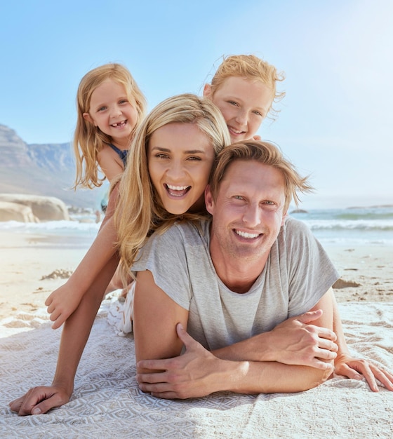 Портрет беззаботной семьи, отдыхающей и сближающейся на пляже две веселые маленькие девочки веселятся с родителями на отдыхе мама и две дочери лежат на папе, наслаждаясь отпуском