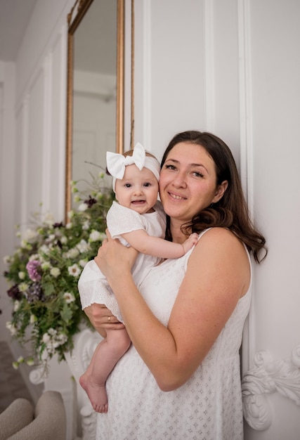 写真 春のデザインの部屋で赤ん坊の娘と白人のブルネットのお母さんの肖像画
