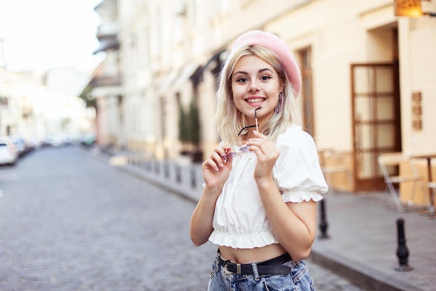 Foto portrait of a charming young woman in a beret and glasses on european street