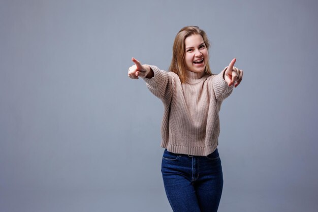 Фото Портрет веселой молодой женщины на сером фоне стены положительные человеческие эмоции выражение лица рекламная концепция удовлетворенность клиентов