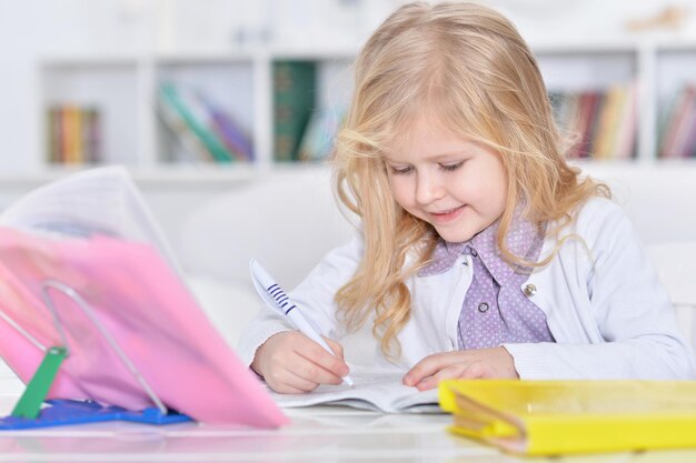 Фото Портрет милой маленькой девочки, делающей домашнее задание