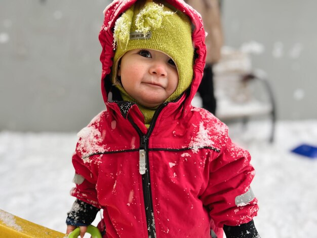 写真 雪の中に立って面白い帽子をかぶった可愛い幼児の肖像画