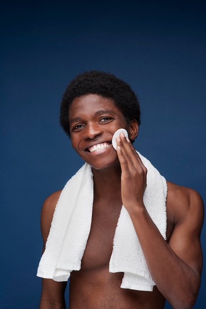 Фото Портрет красивого мужчины, улыбающегося, вытирая лицо салфеткой для макияжа