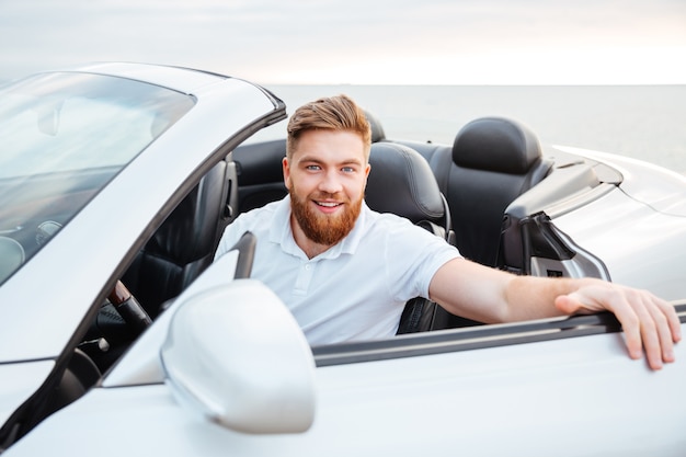 Фото Портрет красивого молодого бородатого мужчины, садящегося в свою машину