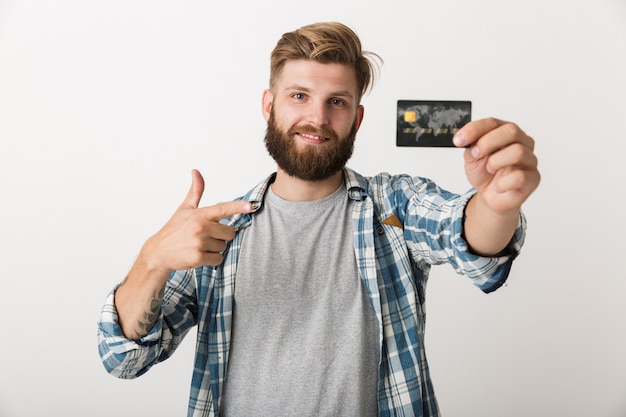Фото Портрет счастливого молодого бородатого мужчины, показывающего кредитную карту, изолированную на белом фоне