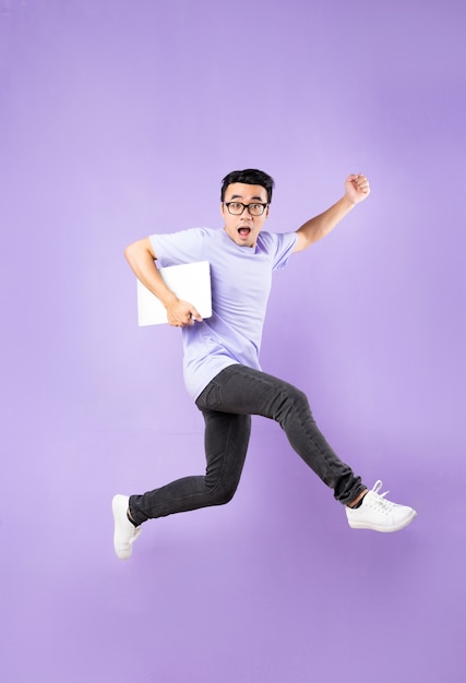 Портрет прыгающего азиатского мужчины, изолированного на фиолетовом фоне