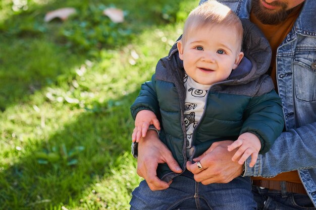 写真 彼の父の膝の上に座っている小さなかわいい男の子の肖像画