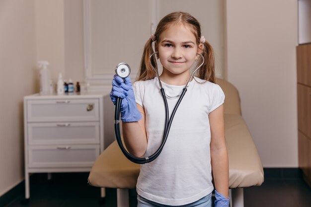 Фото Портрет маленькой девочки в медицинской форме на фоне больницы. фото высокого качества