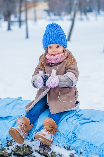 Фото Портрет маленькой девочки с чашкой в руках на фоне снега в парке