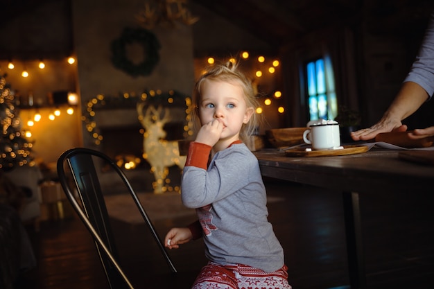 사진 그녀의 할머니는 전통적인 쿠키를 준비하는 동안 마시 멜로 먹는 어린 소녀의 초상화. 개념 아늑한 크리스마스.