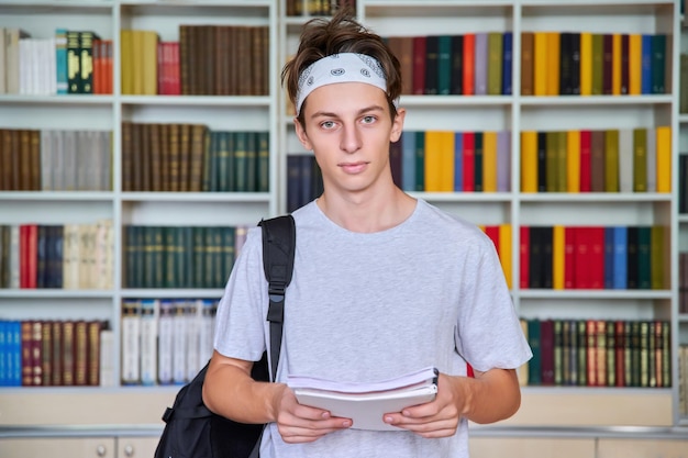 Фото Портрет студента-подростка, смотрящего в камеру в библиотеке