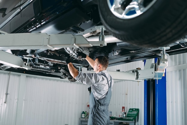 写真 持ち上げられた車を修理する整備士の肖像画。