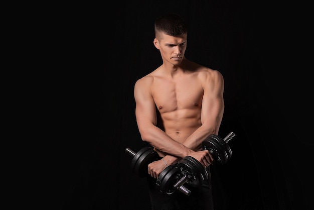 Фото Портрет мускулистого мужчины, поднимающего тяжести на темном фоне