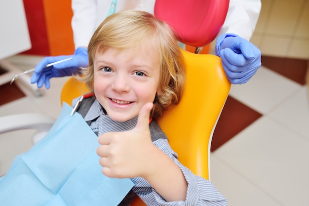 Фото Портрет улыбающегося ребенка с вьющимися волосами на экзамен в стоматологическом кресле.