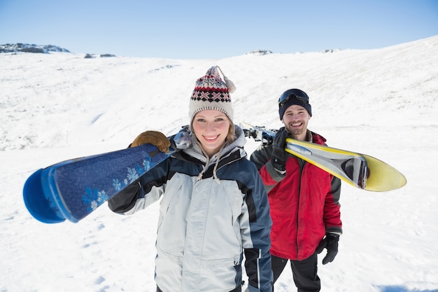 写真 雪の上でスキー板を持つ笑顔のカップルの肖像
