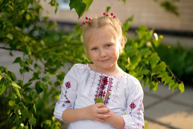 사진 우크라이나어 수 놓은 셔츠에 꽃과 웃는 소녀의 초상화 머리에 빨간 가막살 나무속
