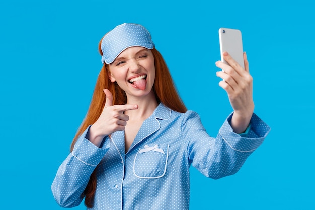 Фото Портрет улыбающейся молодой женщины с смартфоном на синем фоне