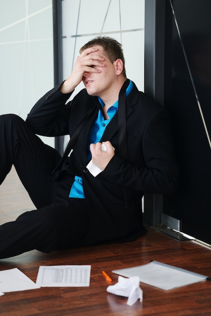 Фото Портрет подчеркнул разочарованный бизнесмен сидит один на полу в офисе