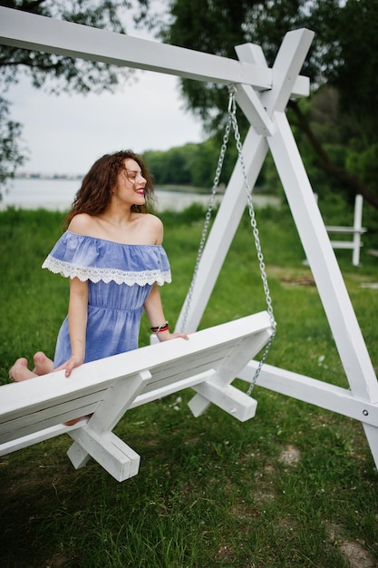 写真 湖畔のブランコに座っている青いマリンスタイルのドレスを着て見事な少女の肖像画